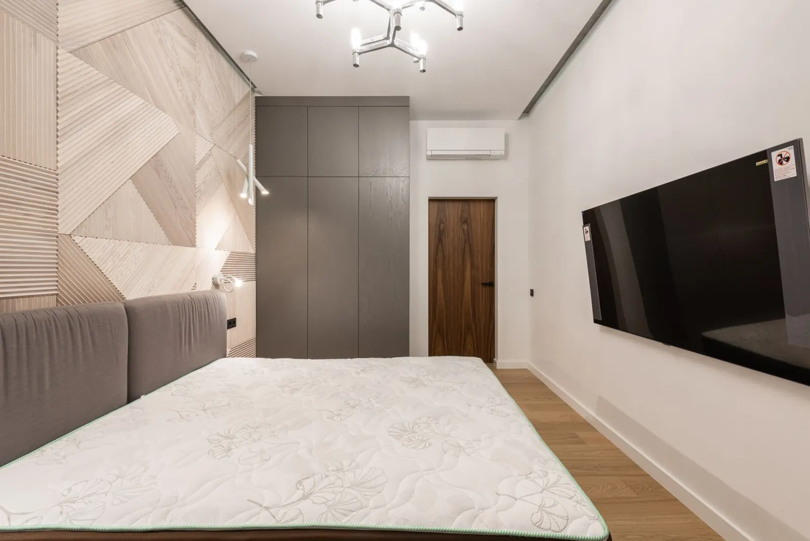 A hotel-style bedroom with a wall-mounted air conditioning unit
