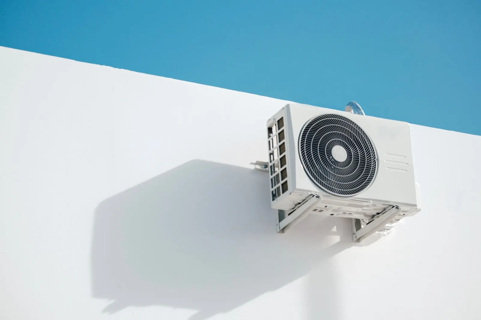 An air conditioning outdoor unit mounted on a white wall